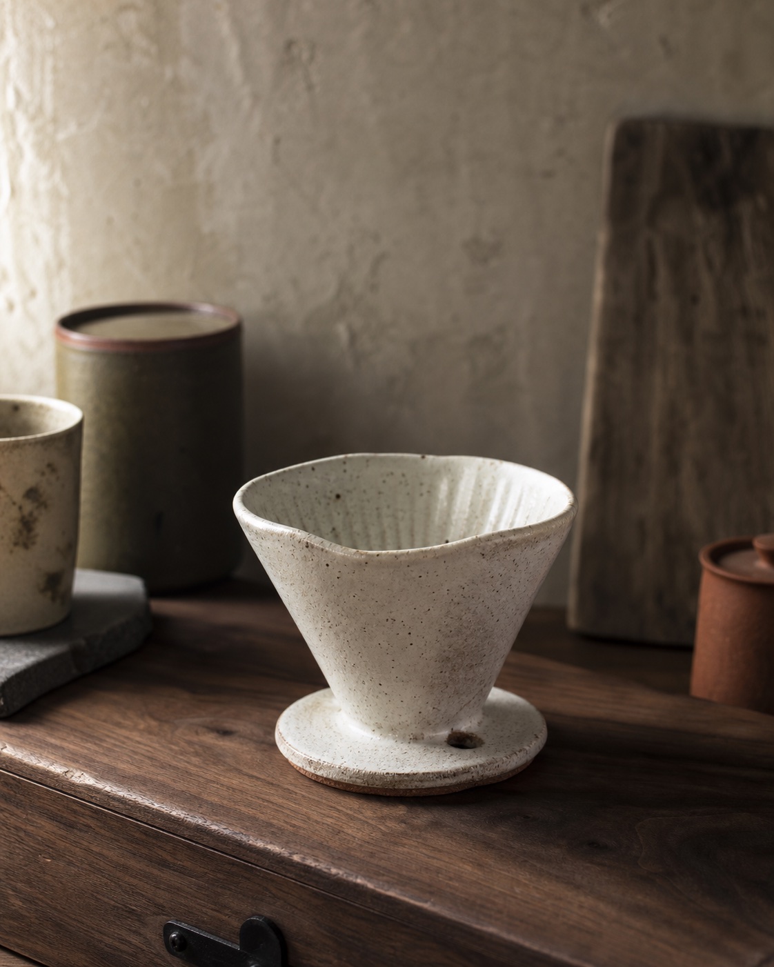 Handmade speckled stoneware Densho coffee dripper on a walnut workshop table